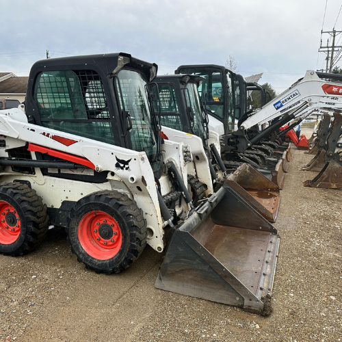 Rental equipment featuring skid steers and skid steer attachments.